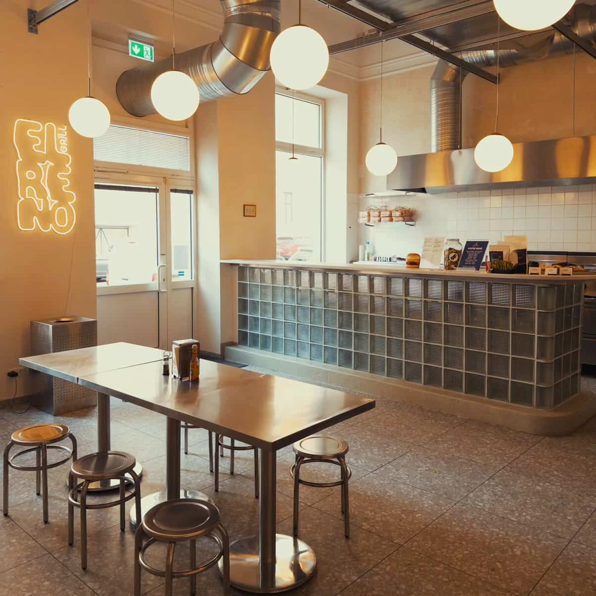 Innenansicht eines Restaurants mit Tischen, Stühlen und Neonlicht